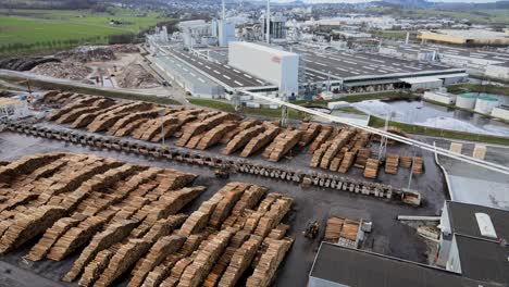 aerial look at wood processing plant in germany, showing polluting smoke and rows of chopped pine logs