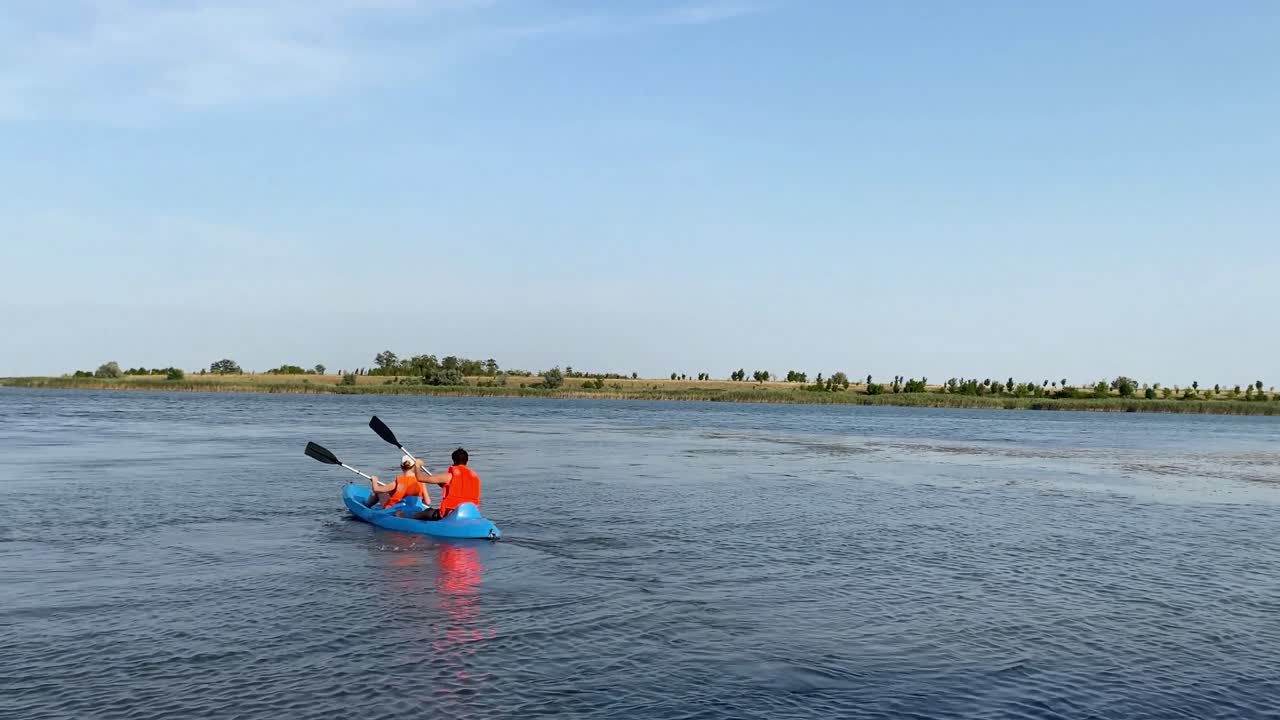 una pareja disfrutando del kayak en un paisaje acuático tranquilo bajo cielos azules claros
