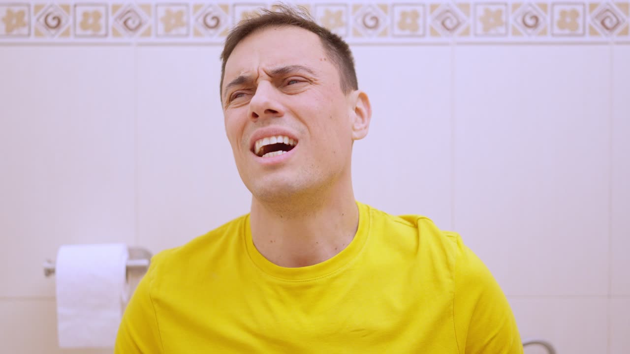 Man suffering from stomach ache while sitting on toilet