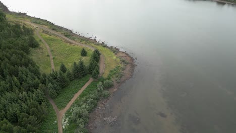 aerial view tracking the lake shoreline, woodland close by