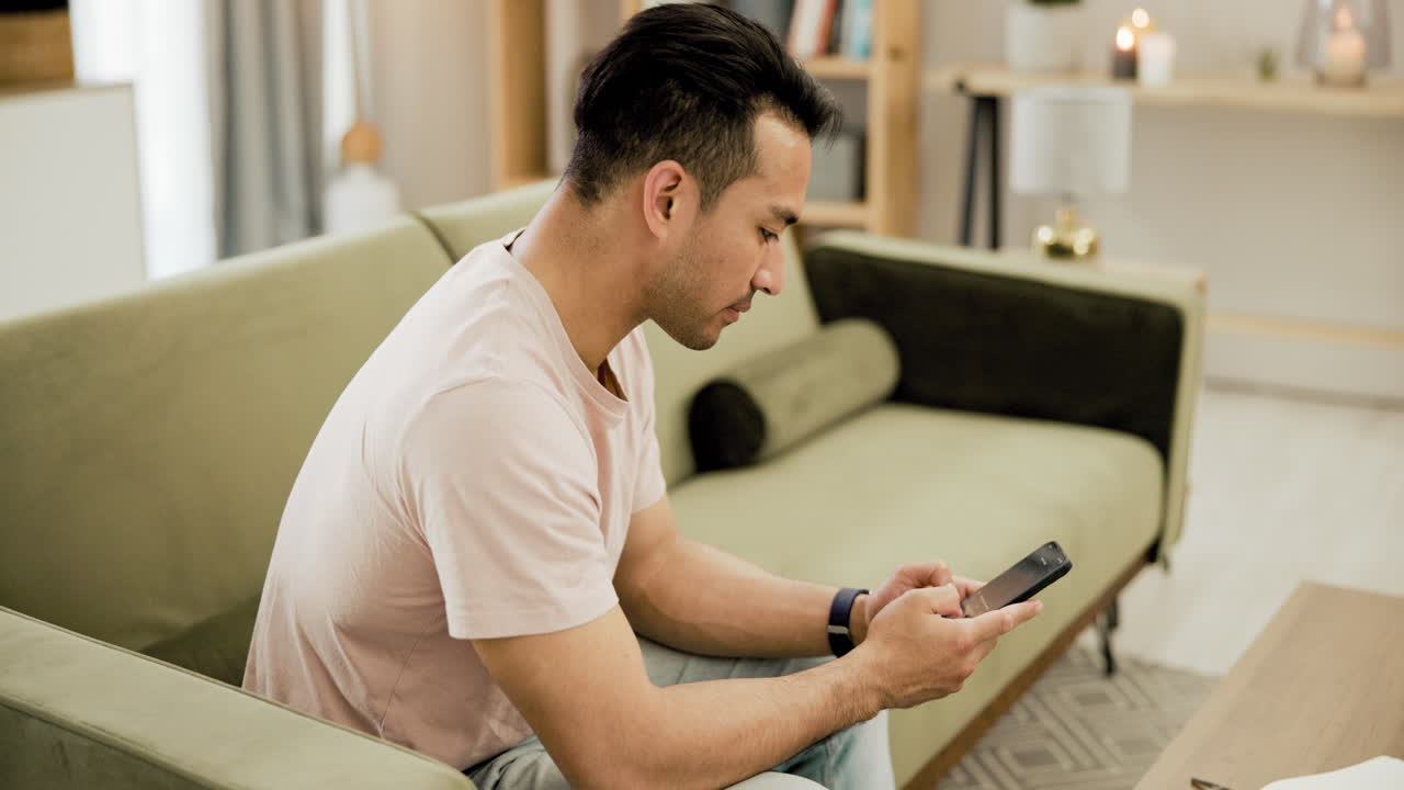 소파에서 스마트폰을 사용하는 남자