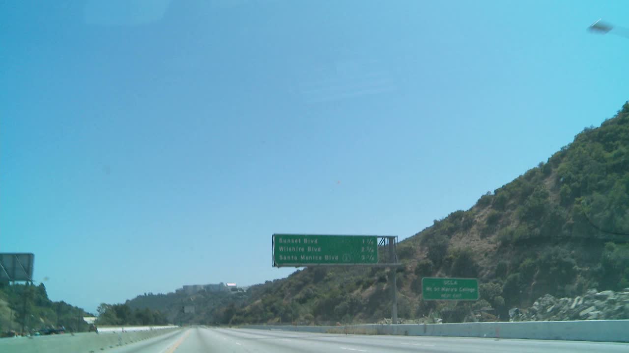 왼쪽의 닫힌 차선에서 건설 차량이 보이는 로스앤젤레스의 빈 고속도로를 따라 운전하는 자동차