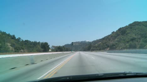 automóvil conduciendo por un tramo vacío de autopista en los ángeles con vehículos de construcción visibles en los carriles cerrados a la izquierda