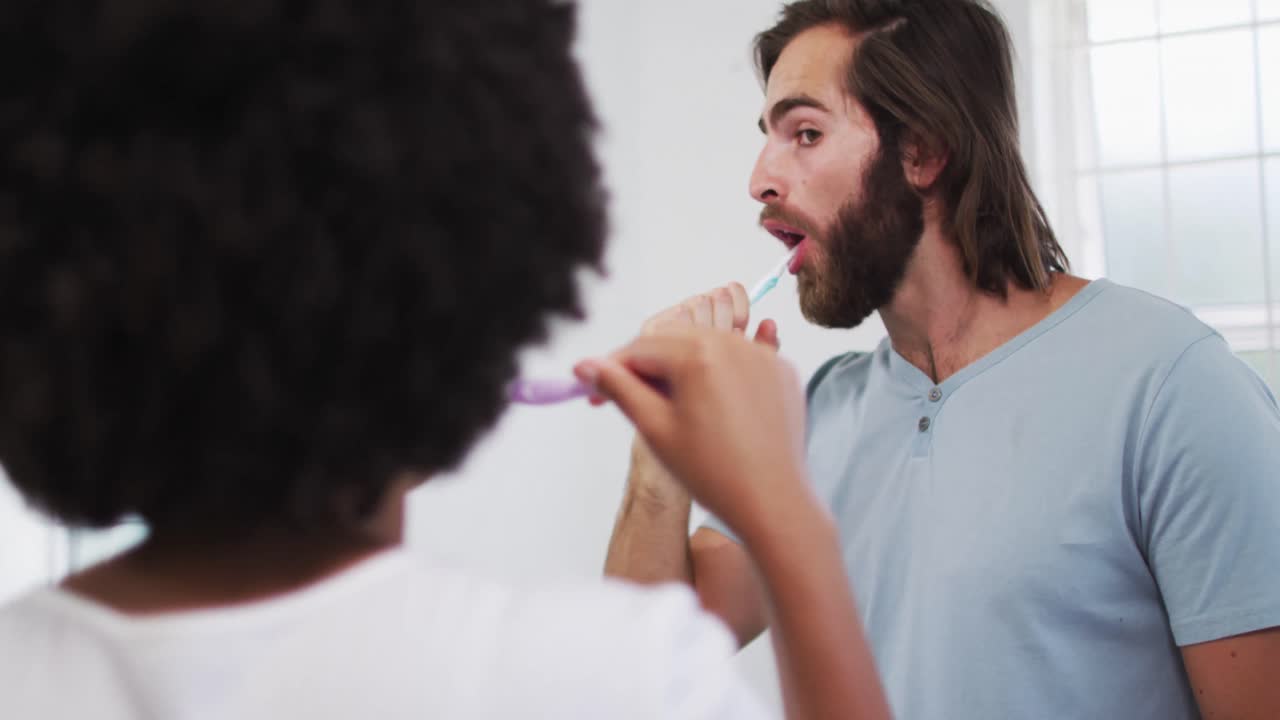 Mixed race couple brushing together in the bathroom