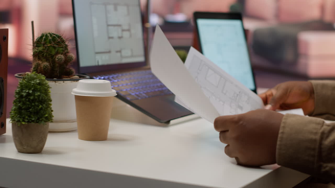 Professional entrepreneur examining blueprints and using digital tools