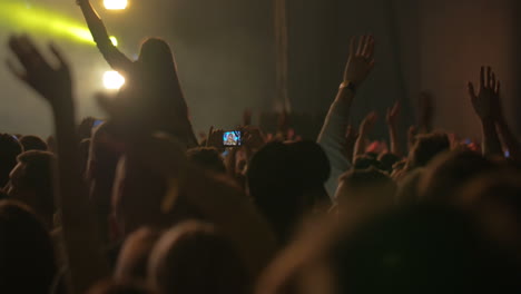 man taking photos of the concert on smartphone