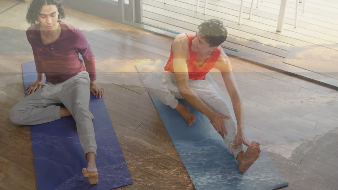 Practicing yoga, two people on mats, ocean waves animation overlaying scene
