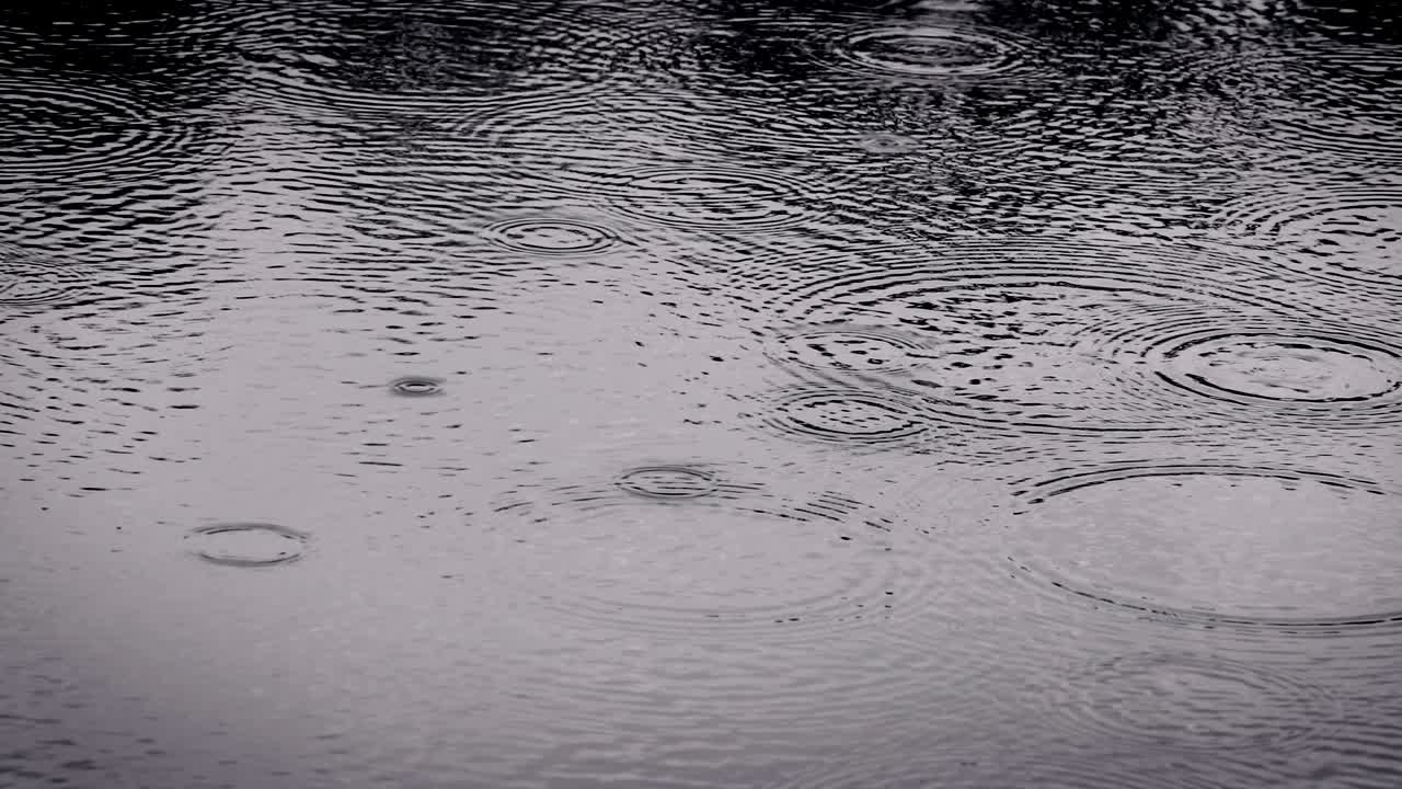 The dark color tone of close up rain water drop falling to the river surface in rainy season , 4K Dci resolution