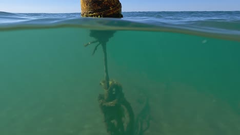 Vista-Inclinada-Hacia-Arriba-Medio-Subacuática-De-Una-Boya-Flotante-Amarilla-Aislada-En-El-Agua-De-Mar