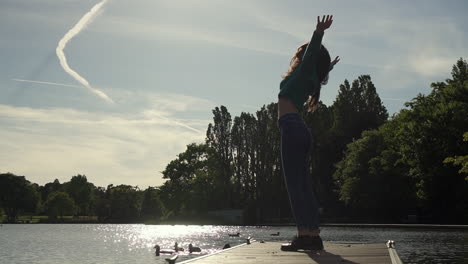 hermosa mujer italiana con los brazos levantados mirando la vista del atardecer sobre el lago