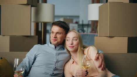 couple celebrating buying house sitting in living room with wine goblets closeup