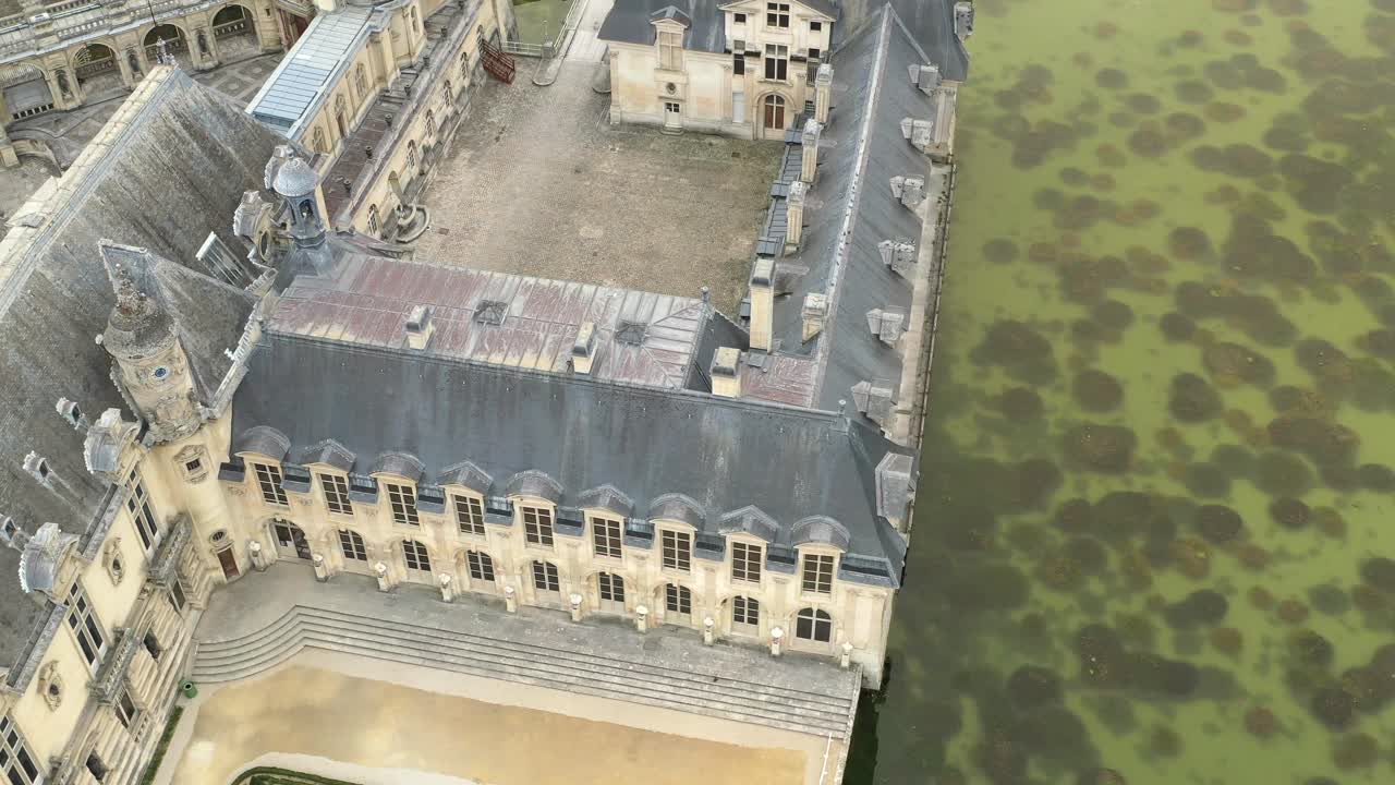 Aerial top down circling view of Chateau de Chantilly wing and moat, France. Historic architecture, French castle, heritage site, travel landmark