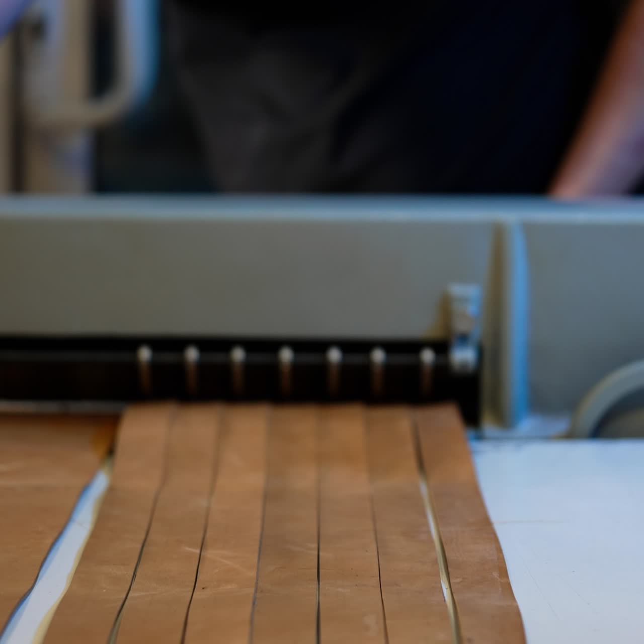 Mestre cortando couro em uma máquina especial na oficina. Artesão profissional trabalhando na indústria de costura. Procedimento para a fabricação de artigos de couro