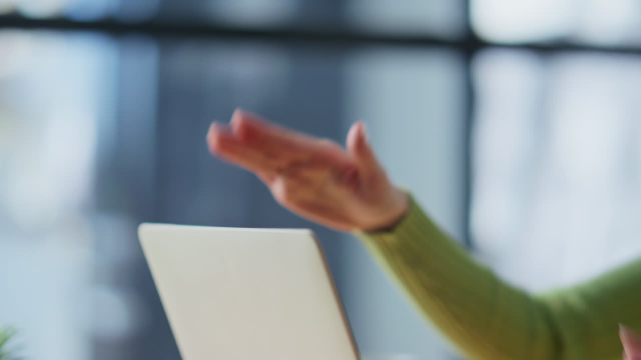 Vihainen nainen puhuu videopuhelussa toimiston lähellä. Nainen sulkee kannettavan tietokoneen.