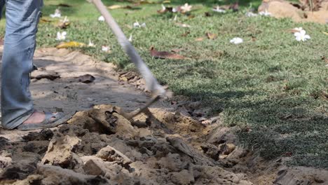 person digging soil with a shovel outdoors.