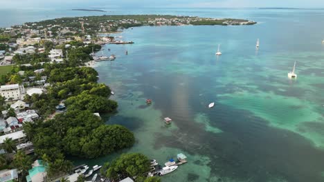 Drohnenansicht-In-Belize,-Die-An-Einem-Bewölkten-Tag-über-Das-Dunkel--Und-Hellblaue-Meer-Der-Karibik-Fliegt,-Einen-Mit-Palmen,-Restaurants-Und-Hotels-Bedeckten-Caye