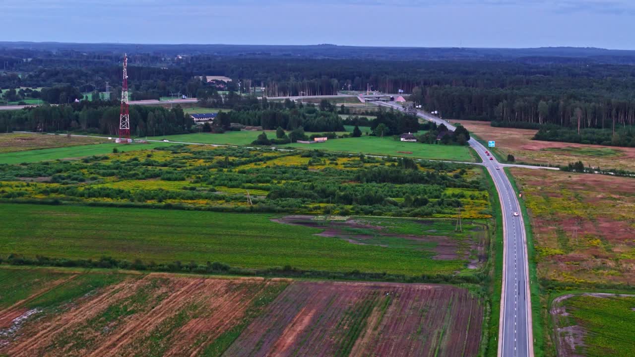 Drone video of Rural road through colorful summer farmland with telecom tower