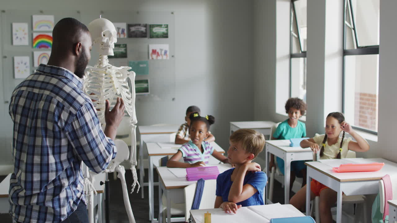 video de un feliz maestro afroamericano con una clase de alumnos diversos durante la lección de anatomía