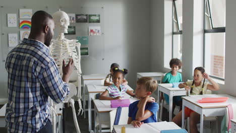 video of happy african american teacher with class of diverse pupils during anatomy lesson