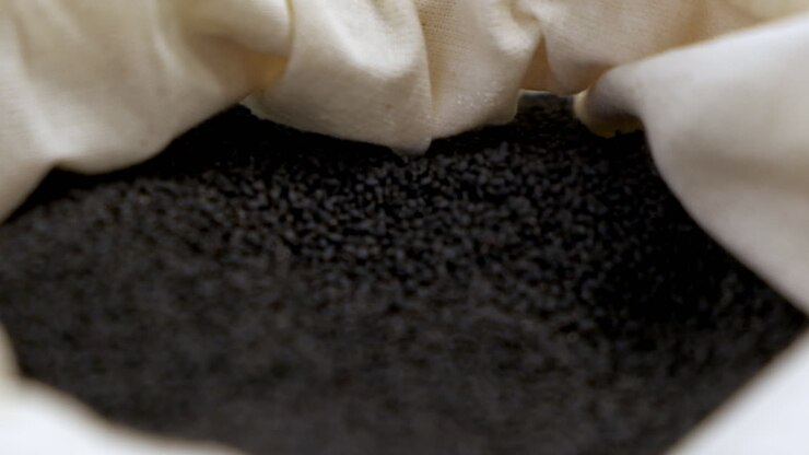 Ripresa in allontanamento con bassa profondità di campo di semi di basilico nero in un sacchetto