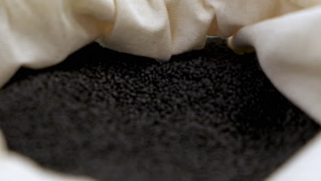 pullback shallow depth shot of black basil seeds in bag