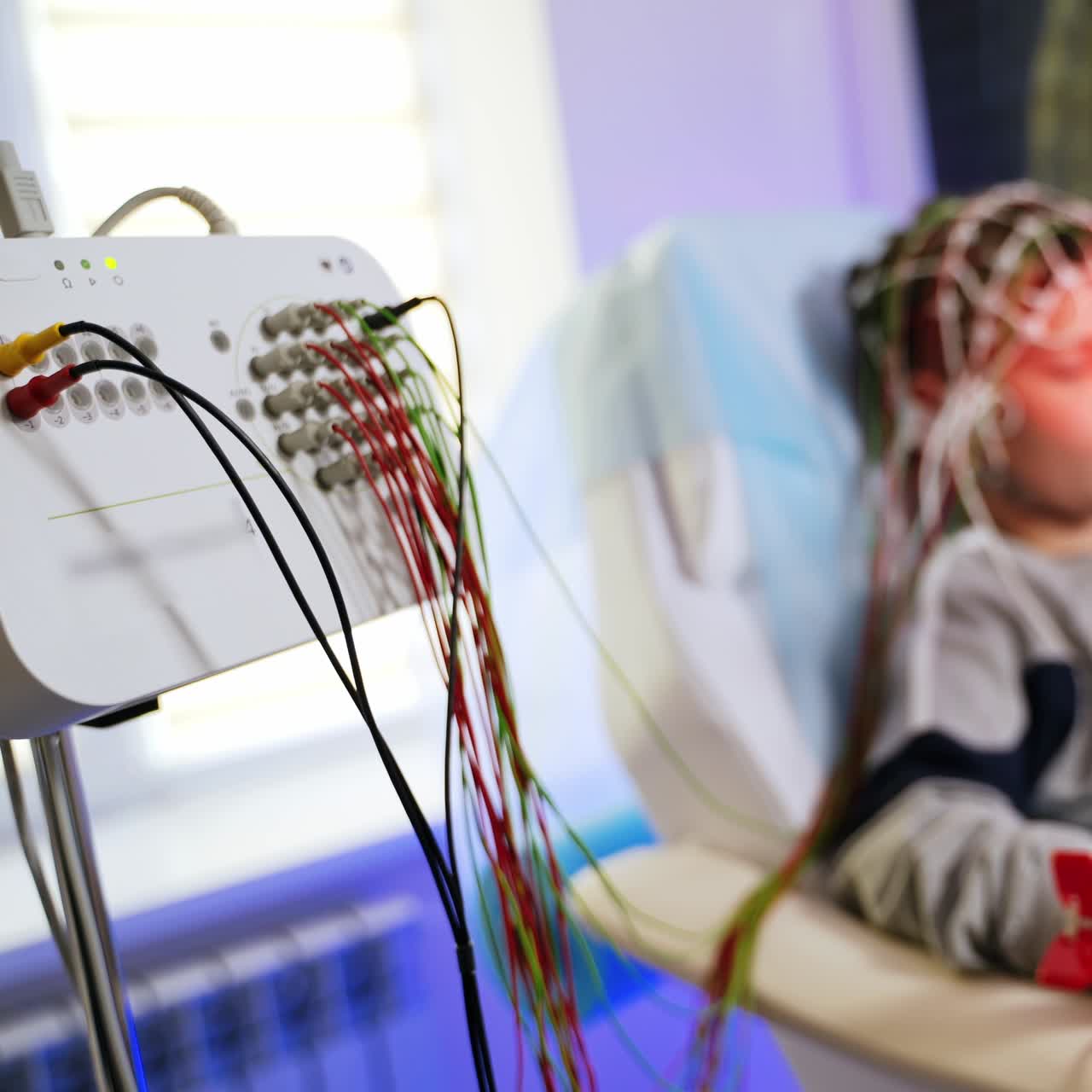 Electrodes attached to the panel and boy sitting at backdrop. Kid is having the brain testing procedure. Blurred background