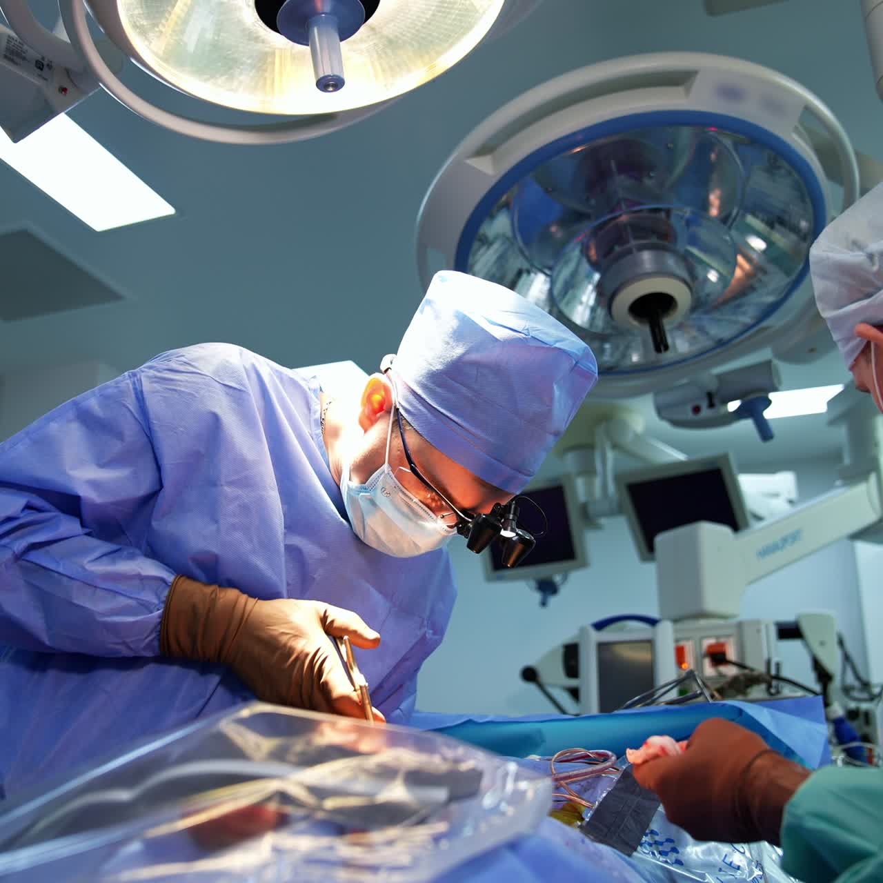 Specialist in neurosurgery operating the patient using tools. Assistant cleans the tool with a napkin. Low angle view