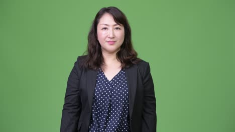 성숙하고 아름다운 아시아 사업가 여성이 엄지손가락을 올리고 있습니다.