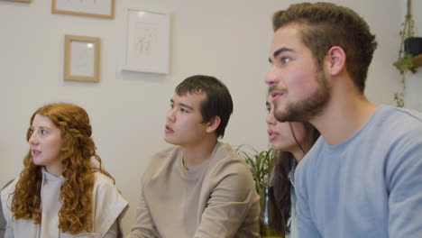 aficionados al deporte comiendo patatas fritas y viendo partidos de fútbol en la televisión