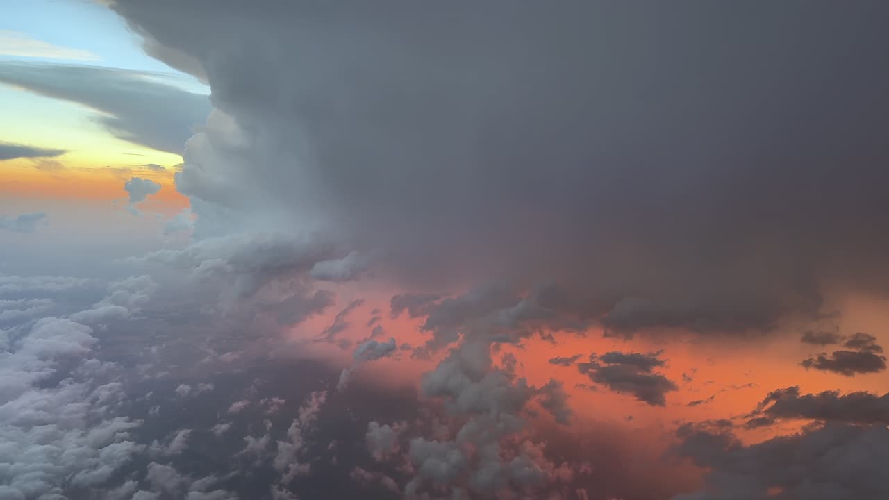 An aerial view of a raging thunderstorm with lightnings and rain through the pilot’s eyes from cockpit. Sunset orange color light breaking through the clouds