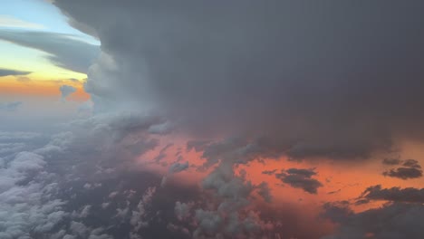 an aerial view of a raging thunderstorm with lightnings and rain through the pilot’s eyes from cockpit. sunset orange color light breaking through the clouds