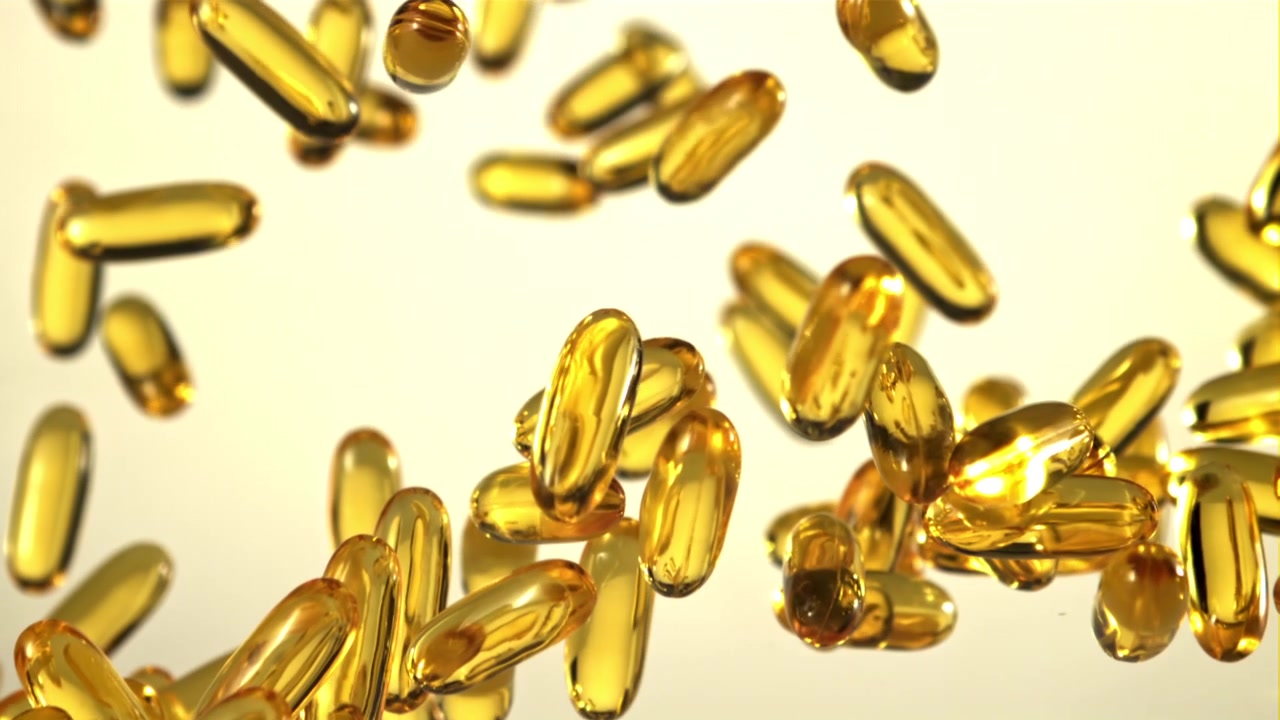 Capsule softgel dorate che cadono al rallentatore