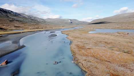 Aerial-drone-tracking-shot-of-a-river,-that-flows-through-a-stony-and-barren-landscape,-sunny-day,-daylight,-no-people,-outdoor