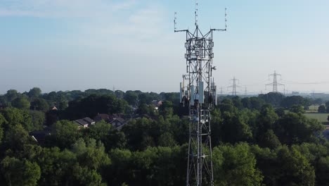 Antena-De-Torre-De-Radiodifusión-5g-En-El-Campo-Británico-Paisaje-Boscoso-Plataforma-Rodante-Aérea-Vista-Derecha-Ascendente