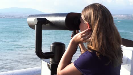 girl looking at the sea through binoculars