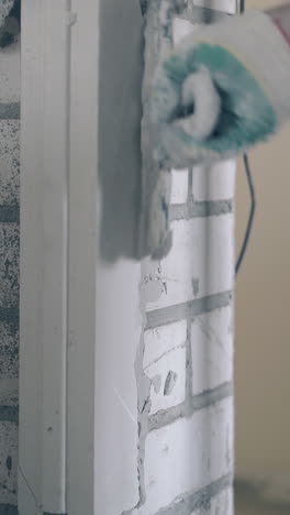 skilled man hand fixes gypsum plasterboard lines on brick wall smearing with putty knife close view