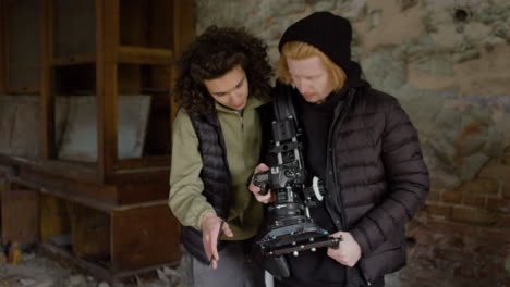 a production worker and cameraman reviewing a scene in a camera in a ruined building