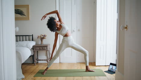 mujer flexible estirando el cuerpo en un lugar acogedor. pelo rizado atleta práctica asana
