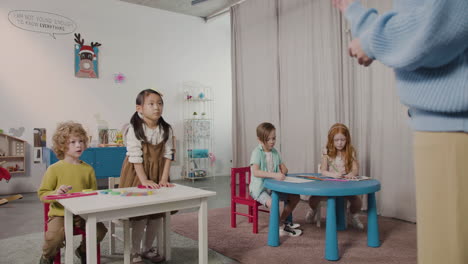 multiethnic pupils at montessori school raising hands to answer a question