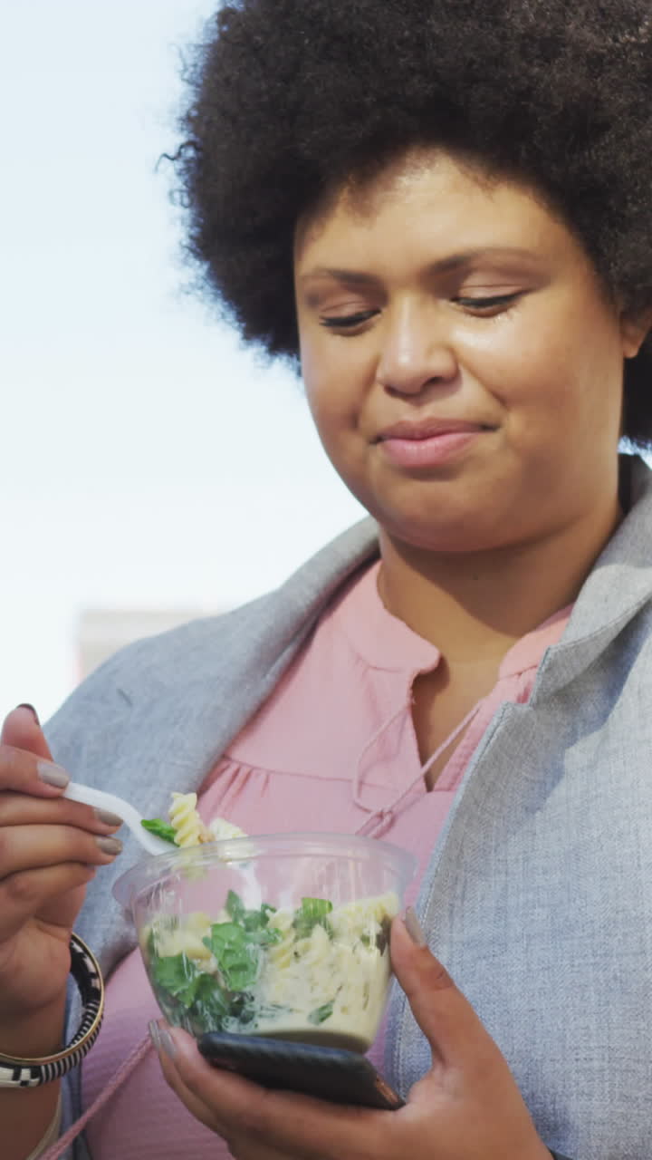 Plus size biracial woman eating salad in city