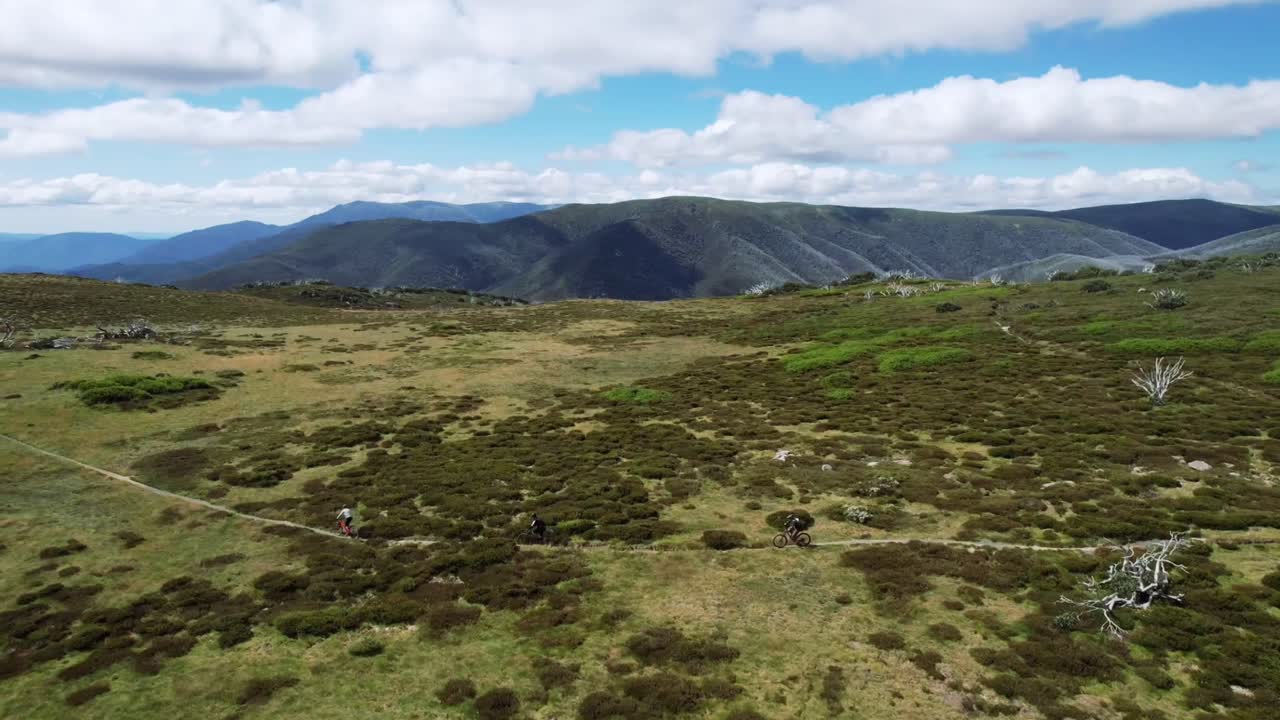 drone volando junto a ciclistas de montaña en la cima de un sendero de montaña
