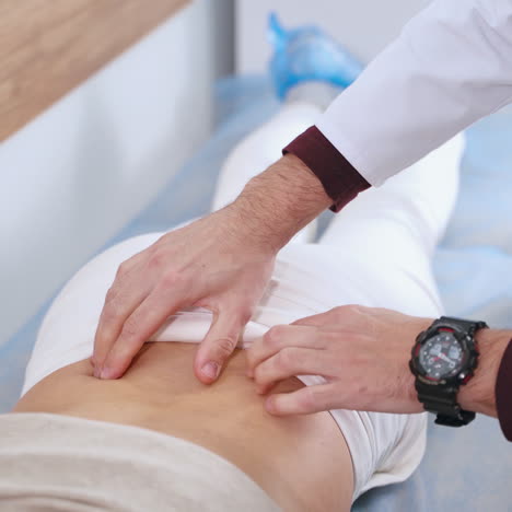 physiotherapist checks the back of a patient. woman is lying on bed and doctor expertises female's spine in clinic. close-up.