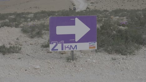 directional race sign on dirt path shows runners where to turn during endurance event, 21km