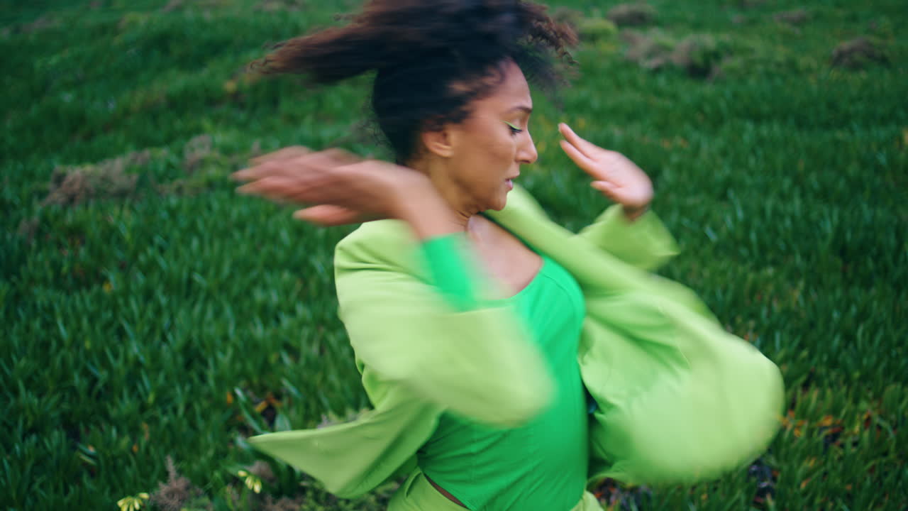 Energetic woman performer dancing on green grass. Girl practicing contemporary.