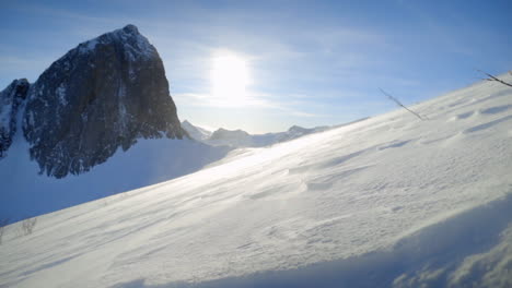 high winds blowing snow over the ground on a high altitude mountain