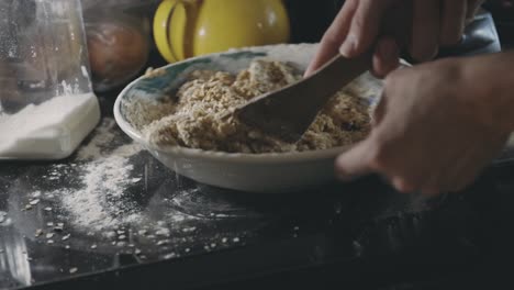 baker mixing batter of cookie with oats on a bowl