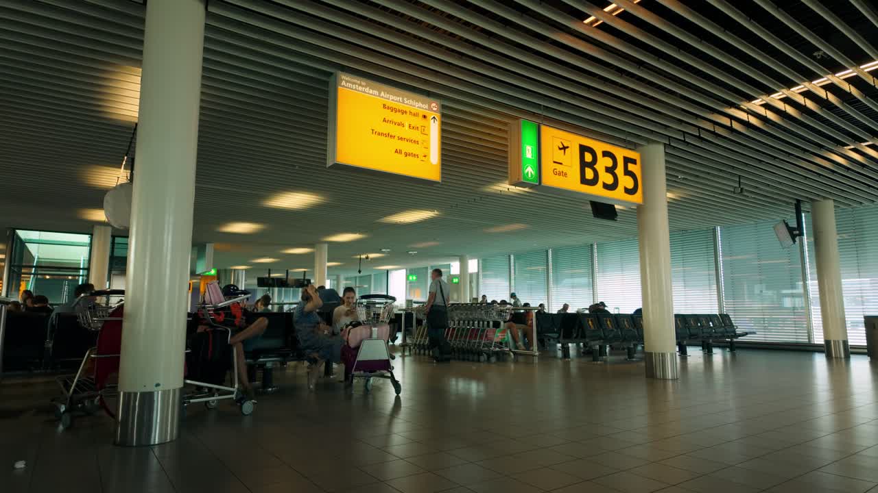 Airport terminal with people and signs at Amsterdam Schiphol