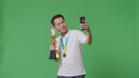 man celebrating a victory with trophy and selfie