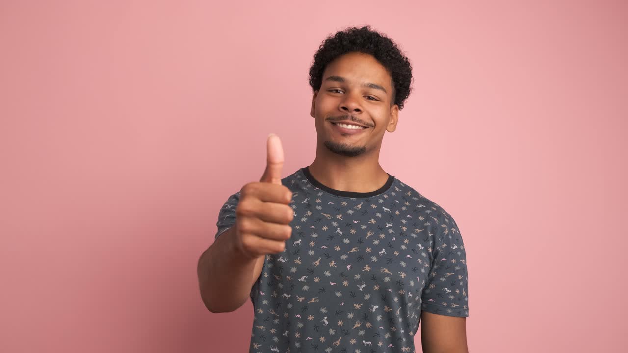 Happy man showing thumbs up in pink studio