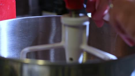 Close-up-of-hand-cracking-an-egg-into-a-mixing-bowl-on-a-stand-mixer